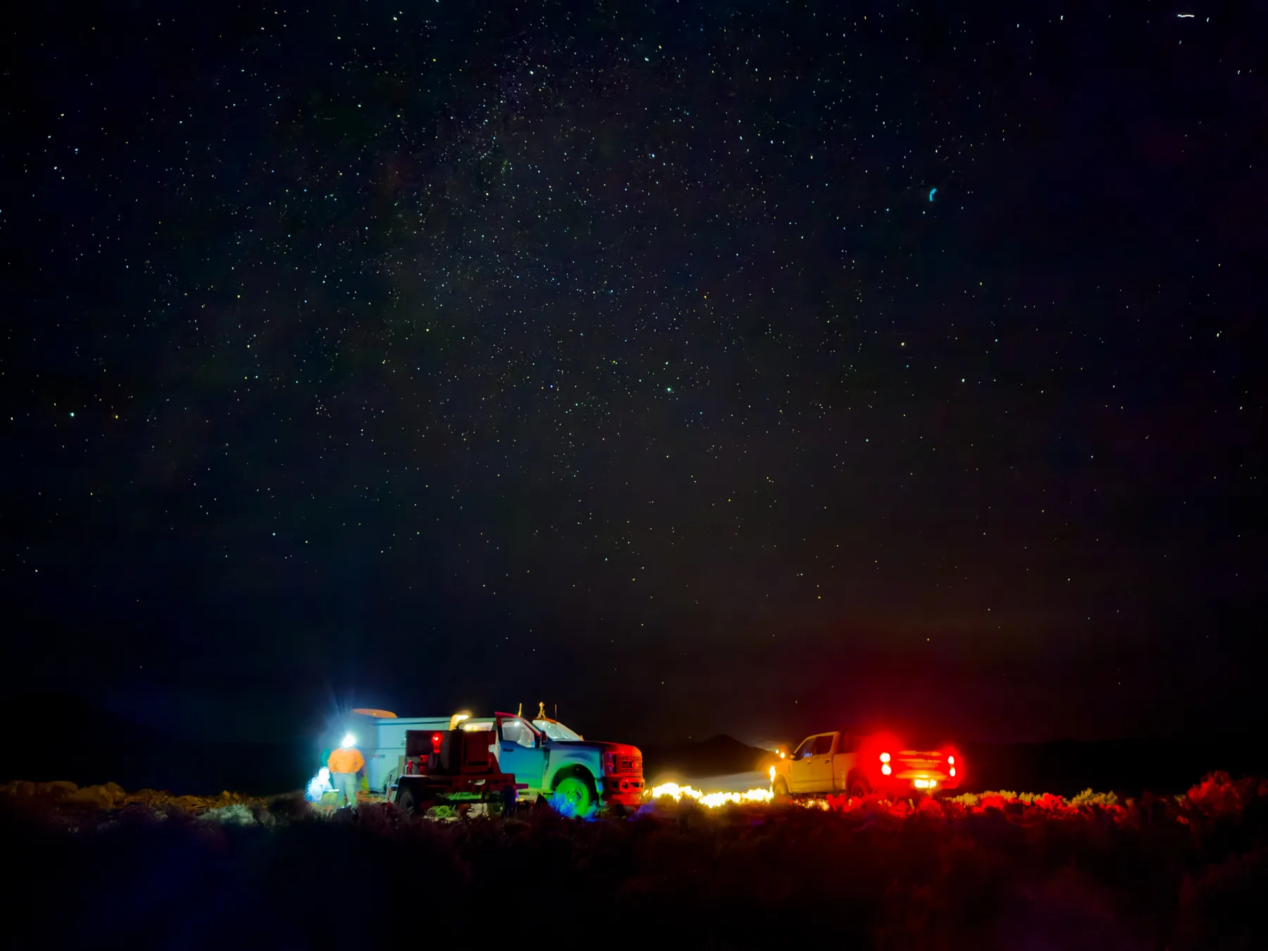 Survey trucks and field crew working at night beneath a star-filled sky